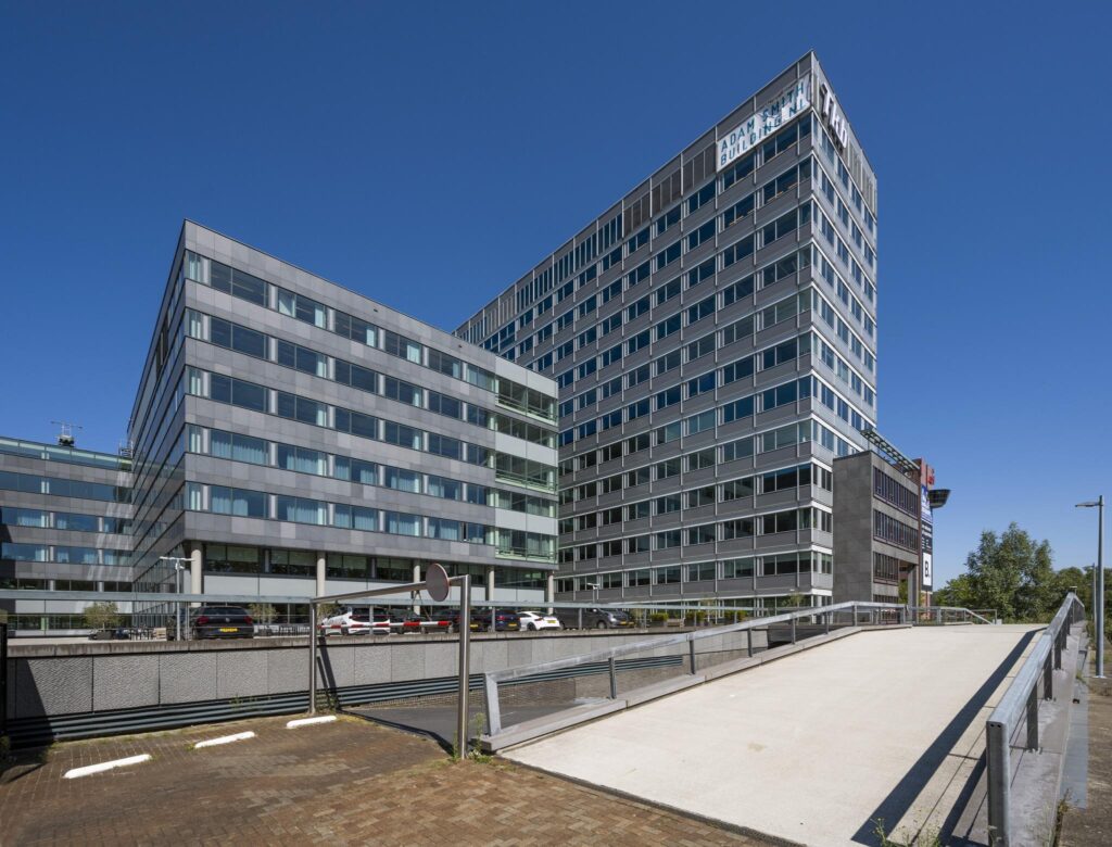Kantoorcomplex aan de Thomas R. Malthusstraat met moderne glazen gevels en parkeergelegenheid op de voorgrond.